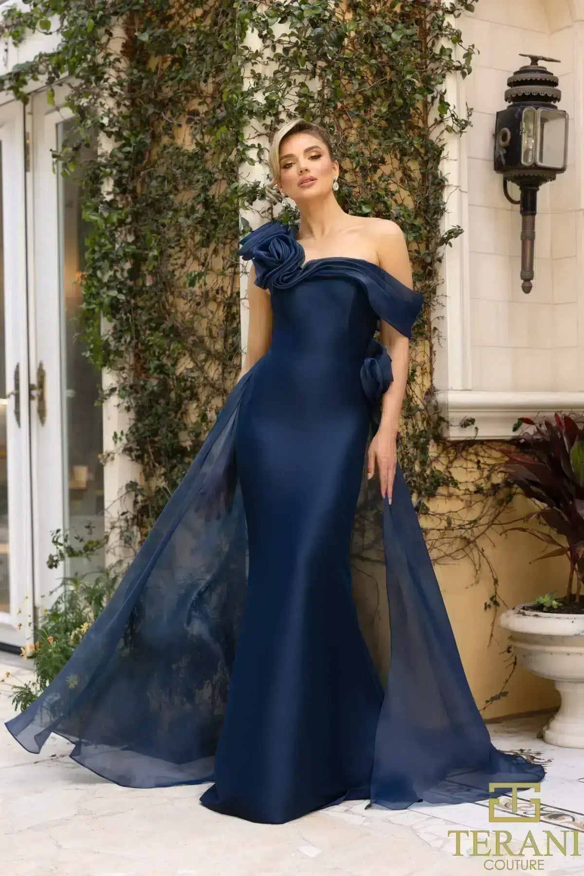 Terani Couture 242M3342 Asymmetric Off-Shoulder Gown with rose detailing, available in navy and emerald. Perfect for formal evening events and Mother of the Bride or Groom.