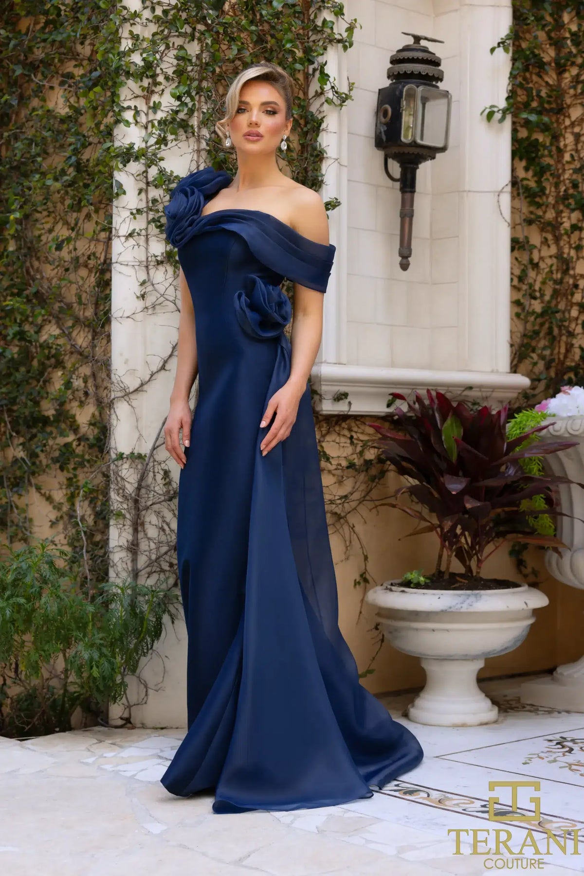 Terani Couture 242M3342 Asymmetric Off-Shoulder Gown with rose detailing, available in navy and emerald. Perfect for formal evening events and Mother of the Bride or Groom.