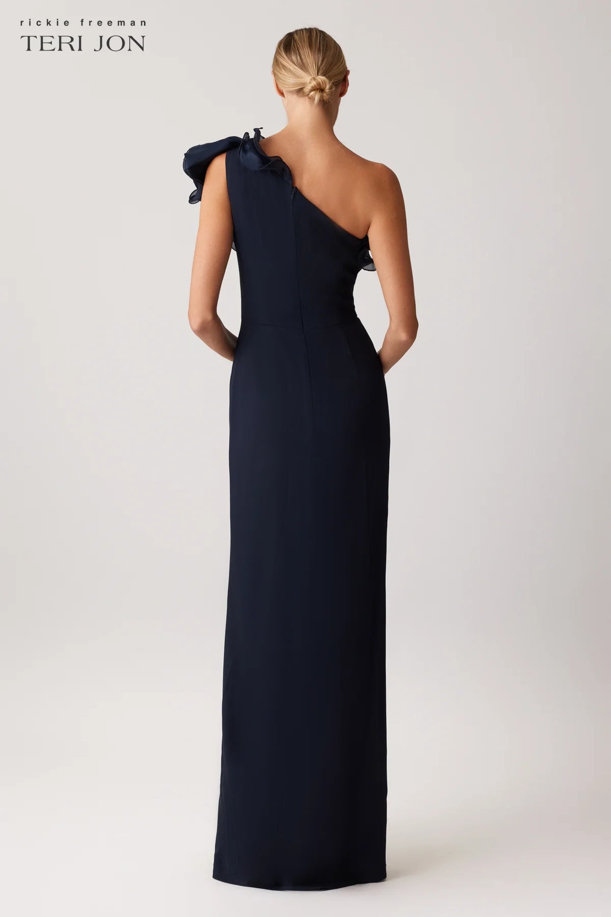 Teri Jon 249043 one-shoulder gown featuring a cascading ruffle detail and fitted silhouette. Perfect for formal evenings and mother of the bride or groom.  Model is wearing the dress in the color navy.  Back View.